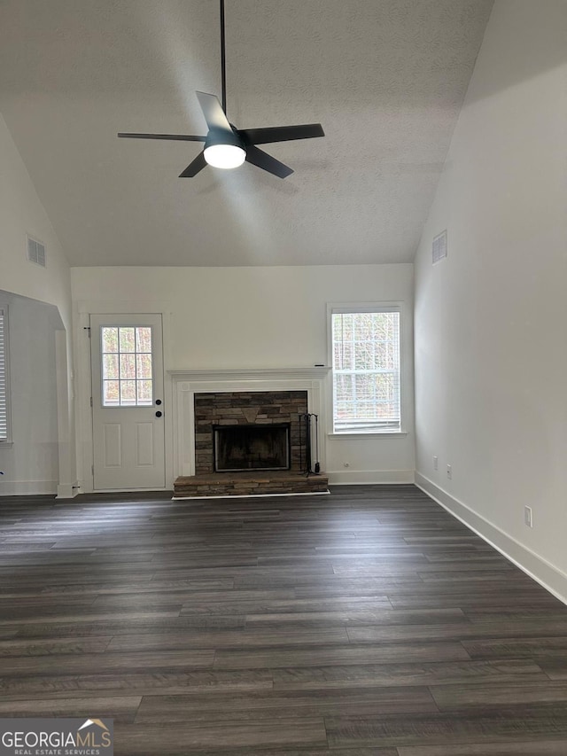 unfurnished living room with a wealth of natural light, ceiling fan, a fireplace, and dark wood-type flooring