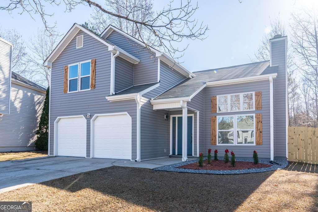 traditional-style home with driveway, an attached garage, a chimney, and fence