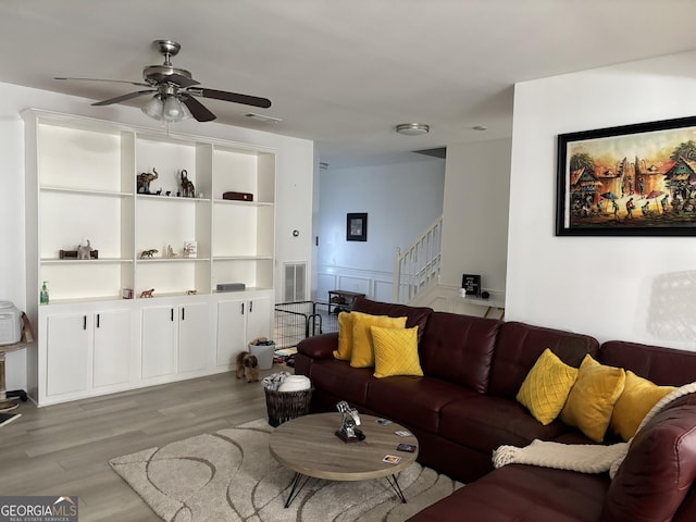 living area with stairway, ceiling fan, visible vents, and wood finished floors