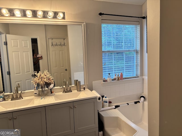 bathroom with double vanity, a garden tub, and a sink