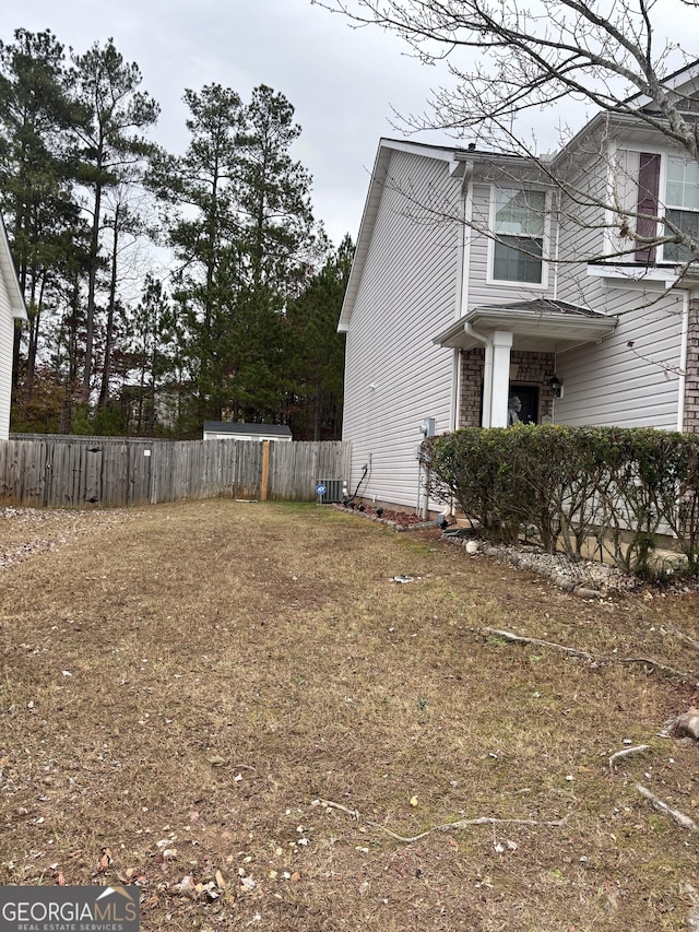 view of side of home with fence, central AC, and brick siding