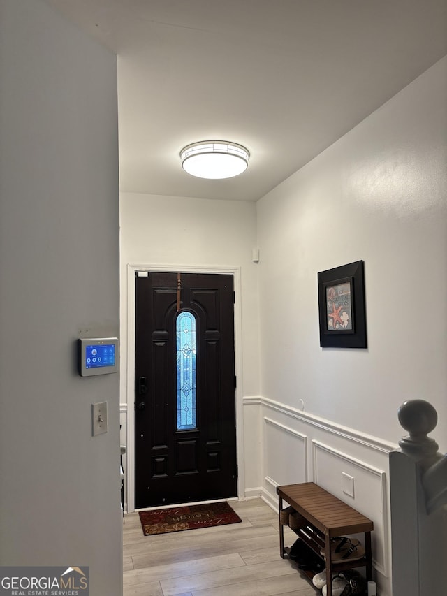 entrance foyer with wainscoting, light wood-type flooring, and a decorative wall