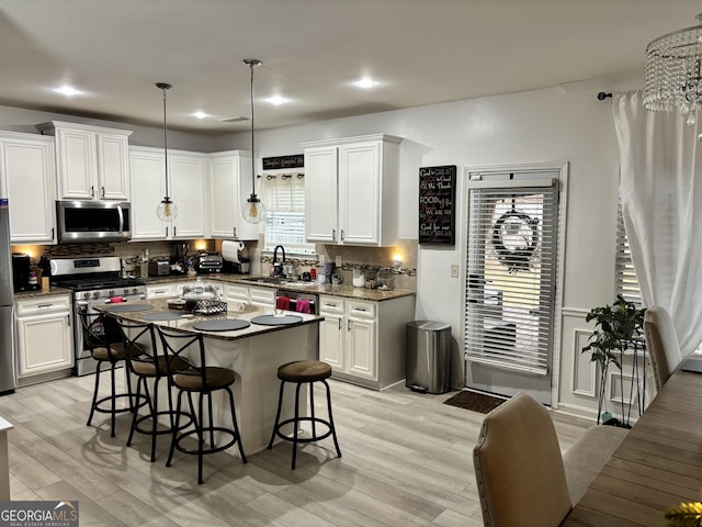 kitchen with white cabinetry, stainless steel appliances, tasteful backsplash, pendant lighting, and a breakfast bar