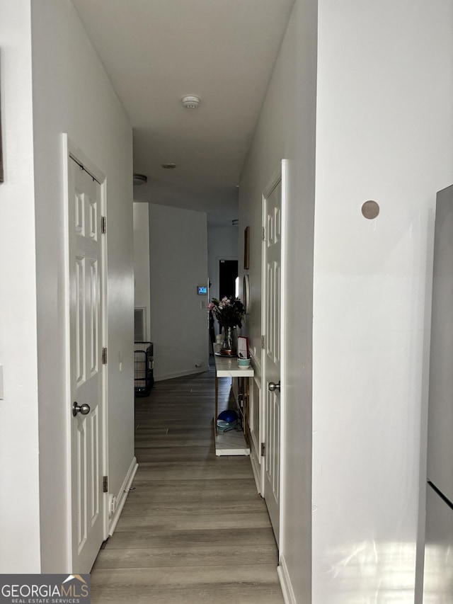 corridor with baseboards and wood finished floors