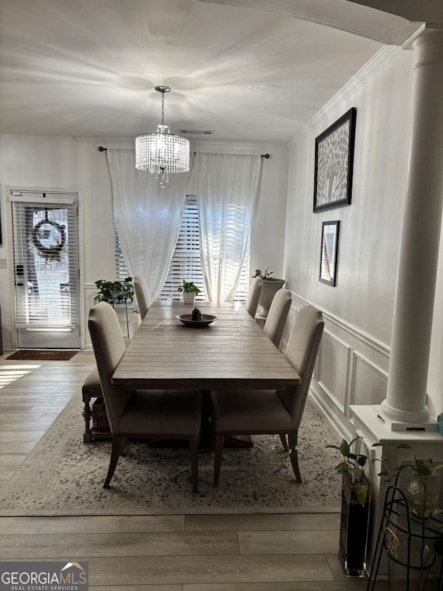 dining room with an inviting chandelier, wood-type flooring, crown molding, and a wealth of natural light