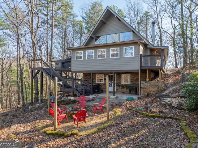 rear view of house with a deck, a patio area, and a fire pit