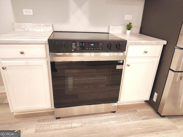 kitchen with white cabinetry, stainless steel appliances, and light hardwood / wood-style floors