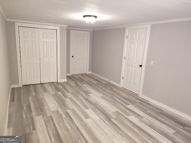 unfurnished bedroom featuring a closet, ornamental molding, and light wood-type flooring