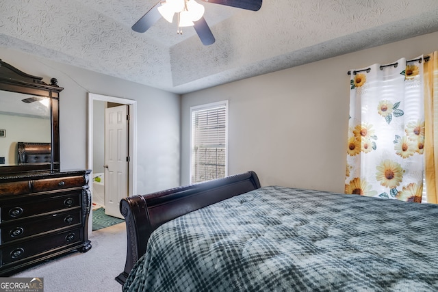 carpeted bedroom with a raised ceiling, ceiling fan, and a textured ceiling