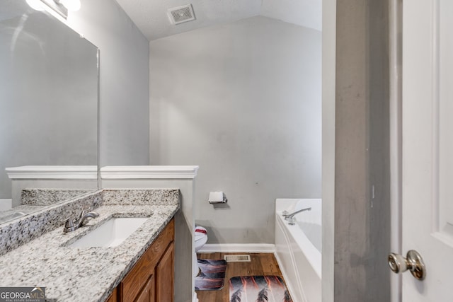 bathroom featuring a bathtub, vanity, vaulted ceiling, hardwood / wood-style floors, and toilet