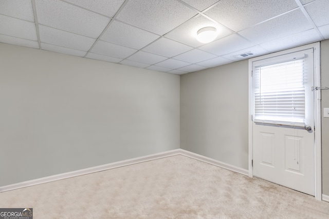 empty room with a paneled ceiling and light colored carpet