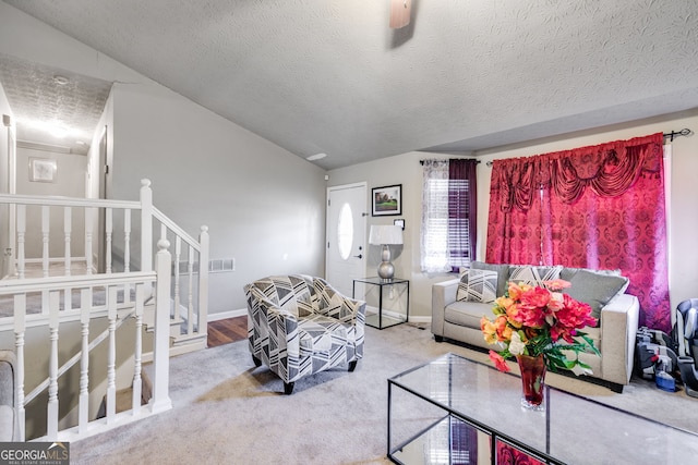 carpeted living room featuring vaulted ceiling, ceiling fan, and a textured ceiling