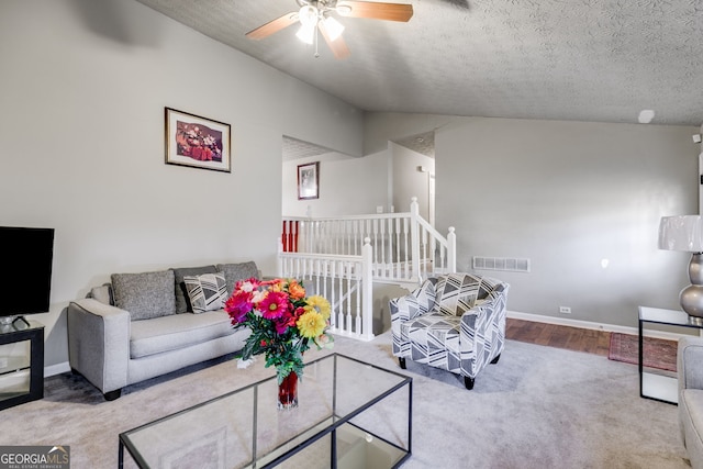 carpeted living room with vaulted ceiling, ceiling fan, and a textured ceiling