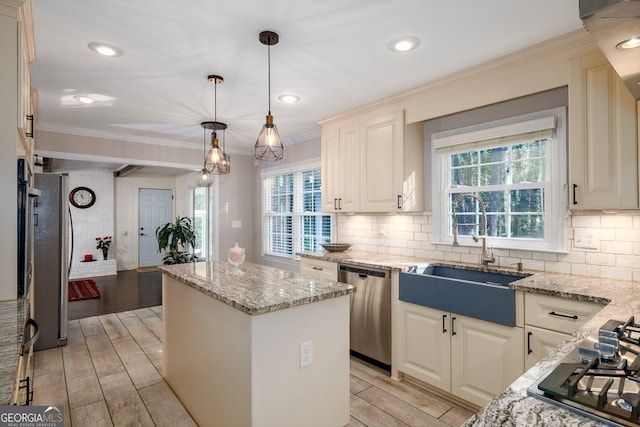 kitchen featuring a kitchen island, sink, hanging light fixtures, light stone counters, and stainless steel appliances