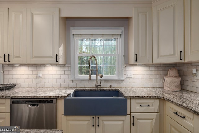 kitchen with light stone counters, stainless steel dishwasher, sink, and backsplash