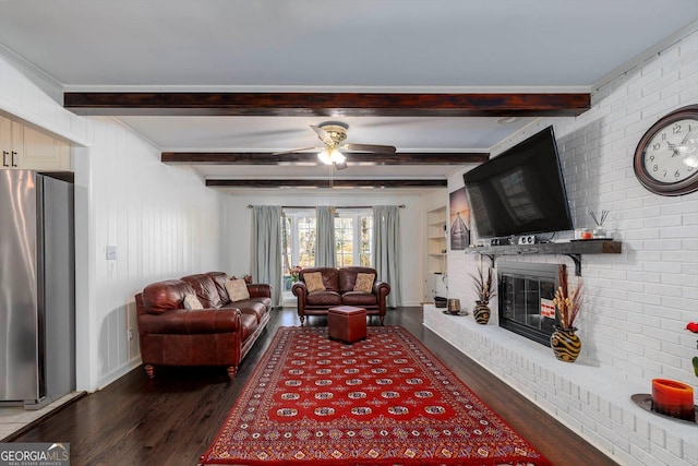 living room featuring beamed ceiling, a brick fireplace, dark hardwood / wood-style floors, and ceiling fan