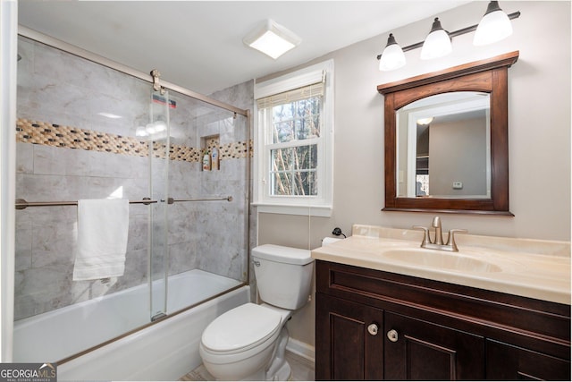 full bathroom featuring vanity, combined bath / shower with glass door, and toilet