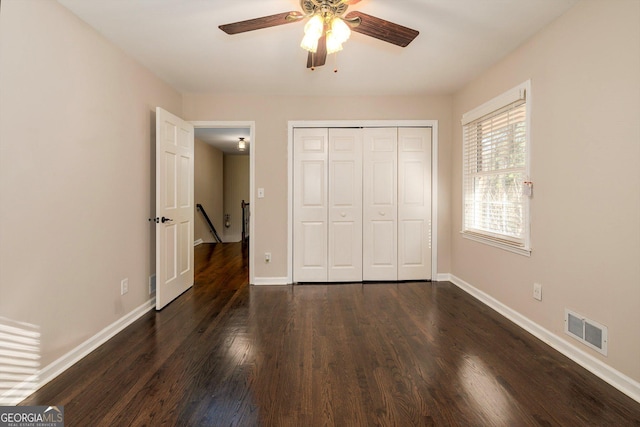 unfurnished bedroom with ceiling fan, dark hardwood / wood-style flooring, and a closet