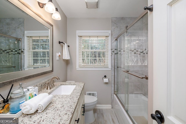 full bathroom with vanity, shower / bath combination with glass door, and toilet