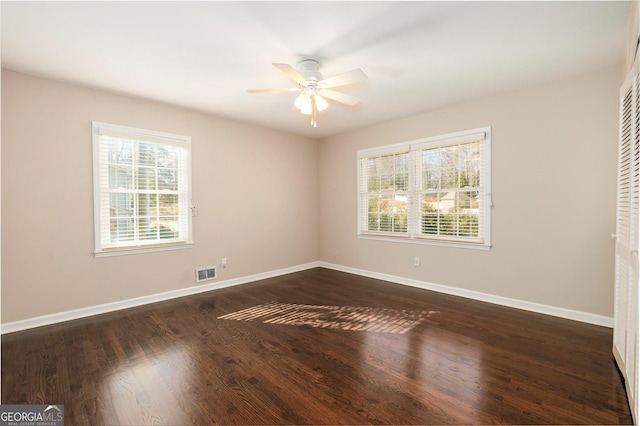 empty room with ceiling fan and dark hardwood / wood-style flooring