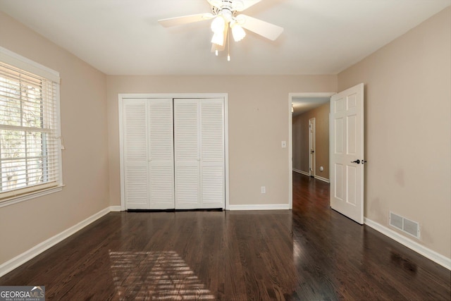 unfurnished bedroom with multiple windows, ceiling fan, dark hardwood / wood-style flooring, and a closet