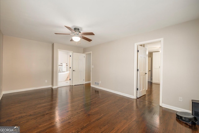 unfurnished bedroom with ensuite bath, dark wood-type flooring, and ceiling fan