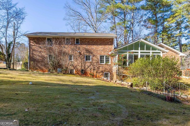 back of property with a yard and a sunroom