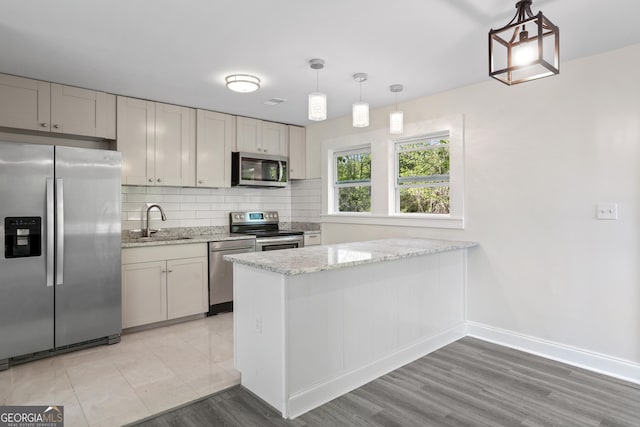 kitchen featuring kitchen peninsula, sink, pendant lighting, and appliances with stainless steel finishes