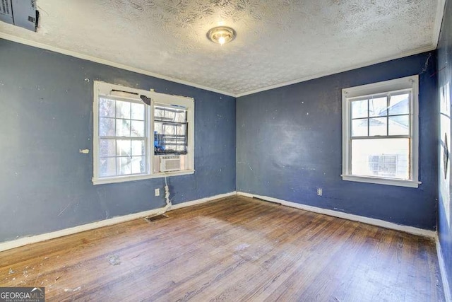 unfurnished room with hardwood / wood-style flooring, crown molding, cooling unit, and a textured ceiling