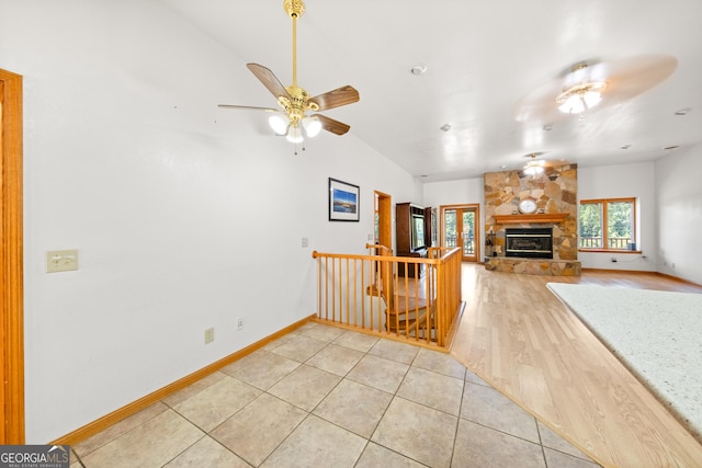 tiled living room with a stone fireplace and ceiling fan