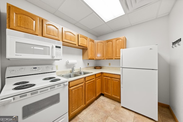 kitchen featuring a paneled ceiling, white appliances, sink, and light tile patterned floors