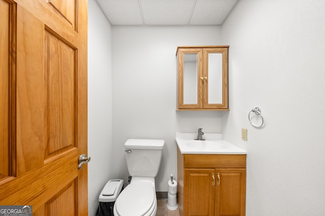 bathroom with a paneled ceiling, vanity, and toilet