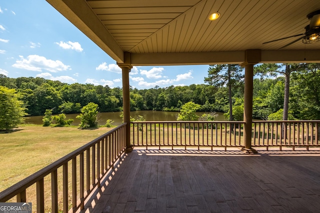 wooden deck with ceiling fan, a yard, and a water view