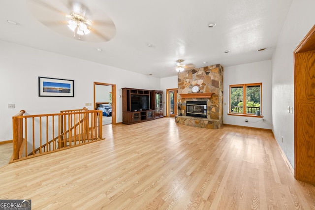 living room featuring a fireplace, light wood-type flooring, and ceiling fan