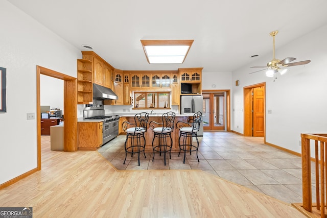 kitchen featuring ceiling fan, stainless steel appliances, light hardwood / wood-style floors, a kitchen bar, and a kitchen island