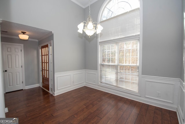 unfurnished dining area with ornamental molding, dark hardwood / wood-style flooring, a chandelier, and a textured ceiling