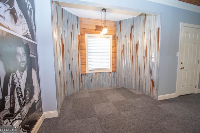 carpeted spare room with crown molding and wood walls