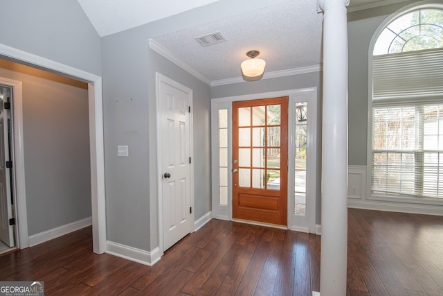 foyer with dark hardwood / wood-style flooring, ornamental molding, decorative columns, and a textured ceiling