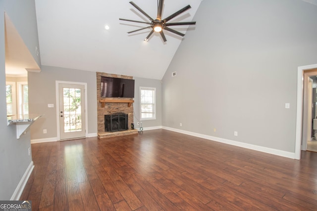 unfurnished living room with plenty of natural light, dark hardwood / wood-style floors, high vaulted ceiling, and a stone fireplace