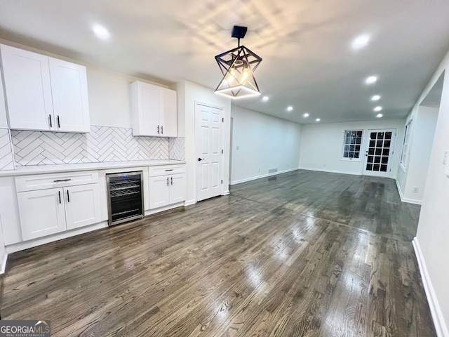 kitchen with dark hardwood / wood-style flooring, tasteful backsplash, beverage cooler, pendant lighting, and white cabinets