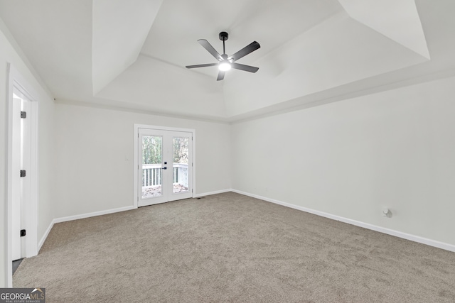 carpeted empty room with french doors, a raised ceiling, and ceiling fan