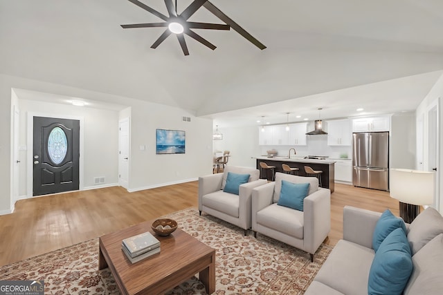 living room featuring light hardwood / wood-style floors, ceiling fan, lofted ceiling, and sink