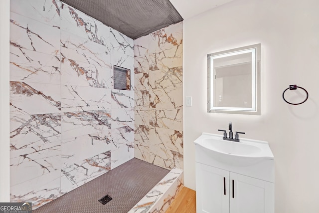 bathroom with a tile shower and vanity