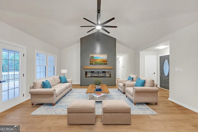 living room with ceiling fan, a fireplace, light hardwood / wood-style floors, and lofted ceiling