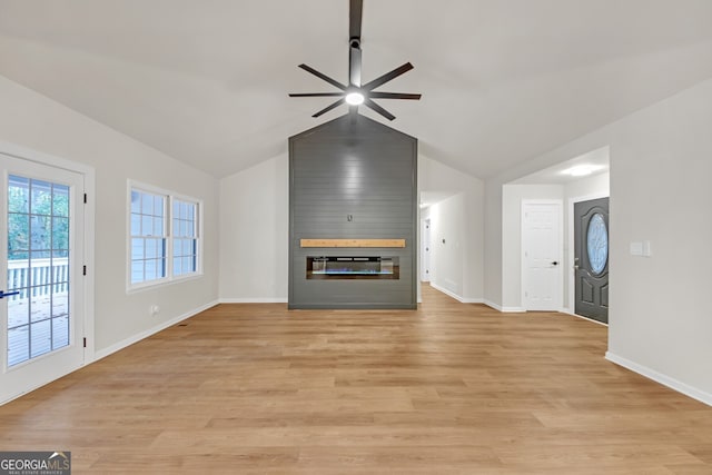 unfurnished living room with light wood-type flooring, a large fireplace, vaulted ceiling, and ceiling fan