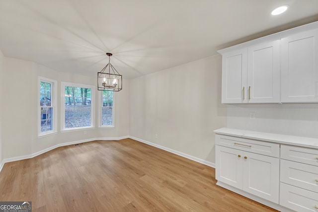 unfurnished dining area with light hardwood / wood-style flooring and a notable chandelier