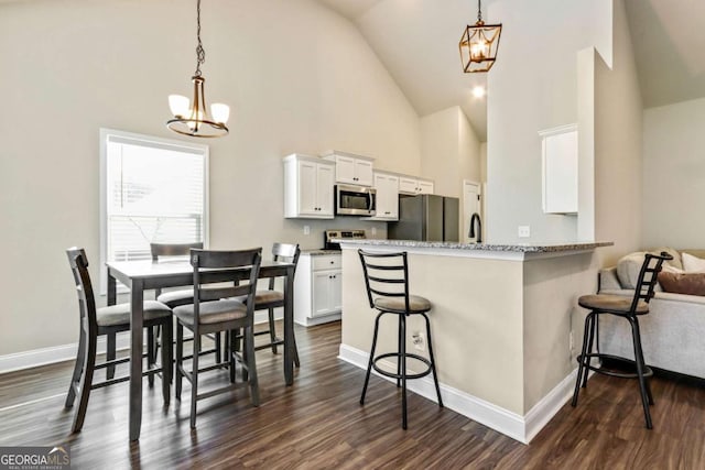 kitchen with an inviting chandelier, a kitchen breakfast bar, decorative light fixtures, white cabinetry, and stainless steel appliances