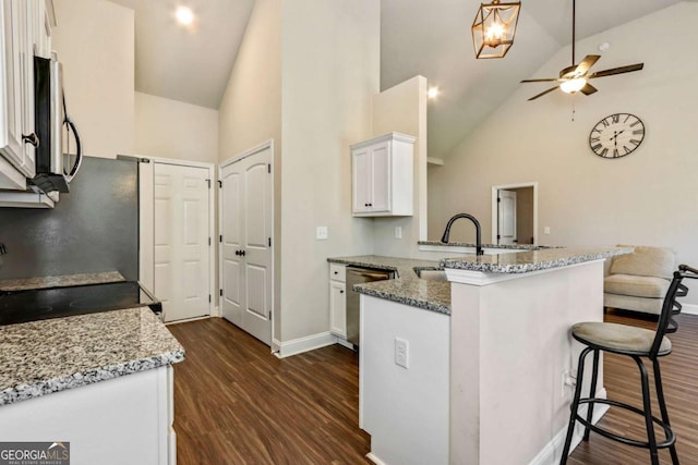 kitchen with kitchen peninsula, stainless steel appliances, white cabinetry, and light stone counters