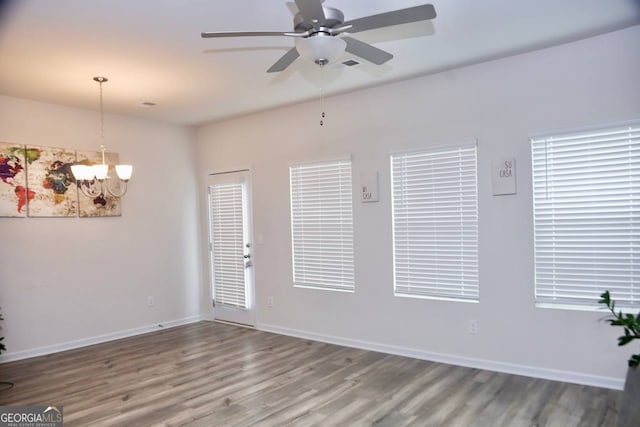 empty room featuring ceiling fan with notable chandelier and hardwood / wood-style flooring