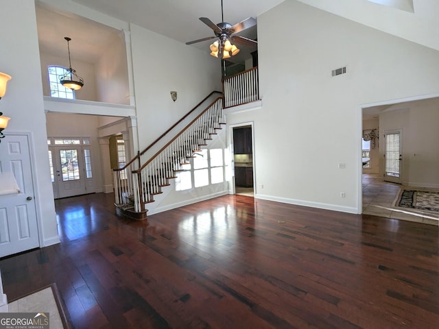 unfurnished living room with ceiling fan, dark hardwood / wood-style flooring, and a towering ceiling